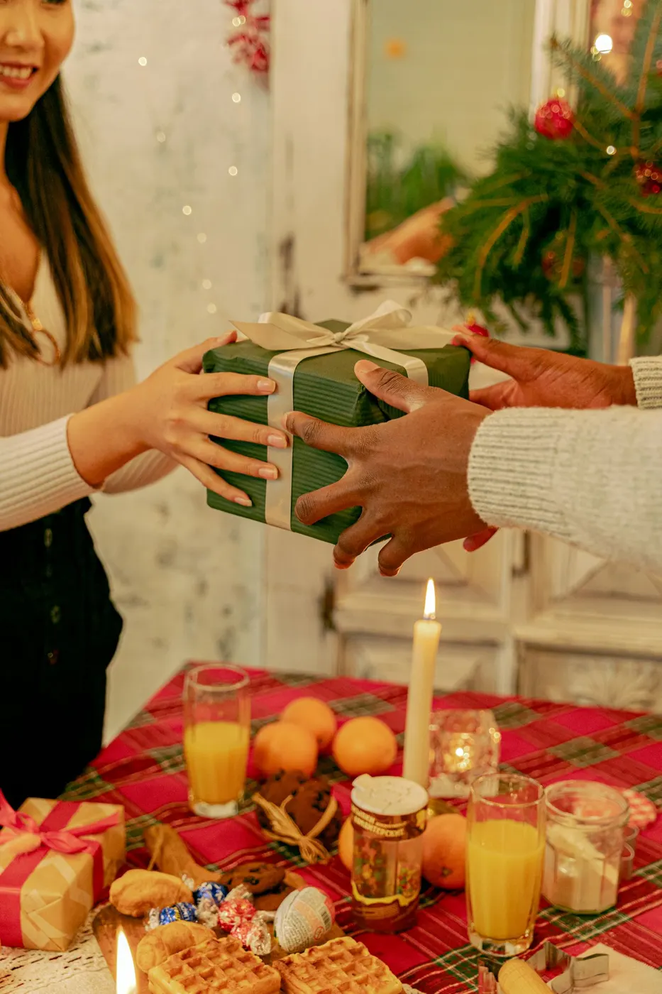 Mains qui se passent un cadeau au-dessus d'une table de fête décorée de bougies