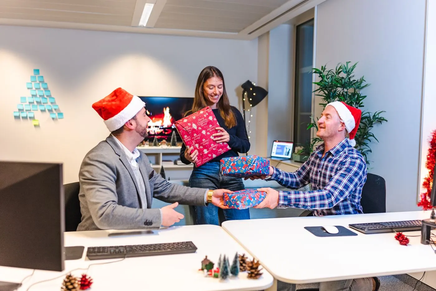 Collègues en bonnets de Noël s'échangeant des cadeaux dans un bureau